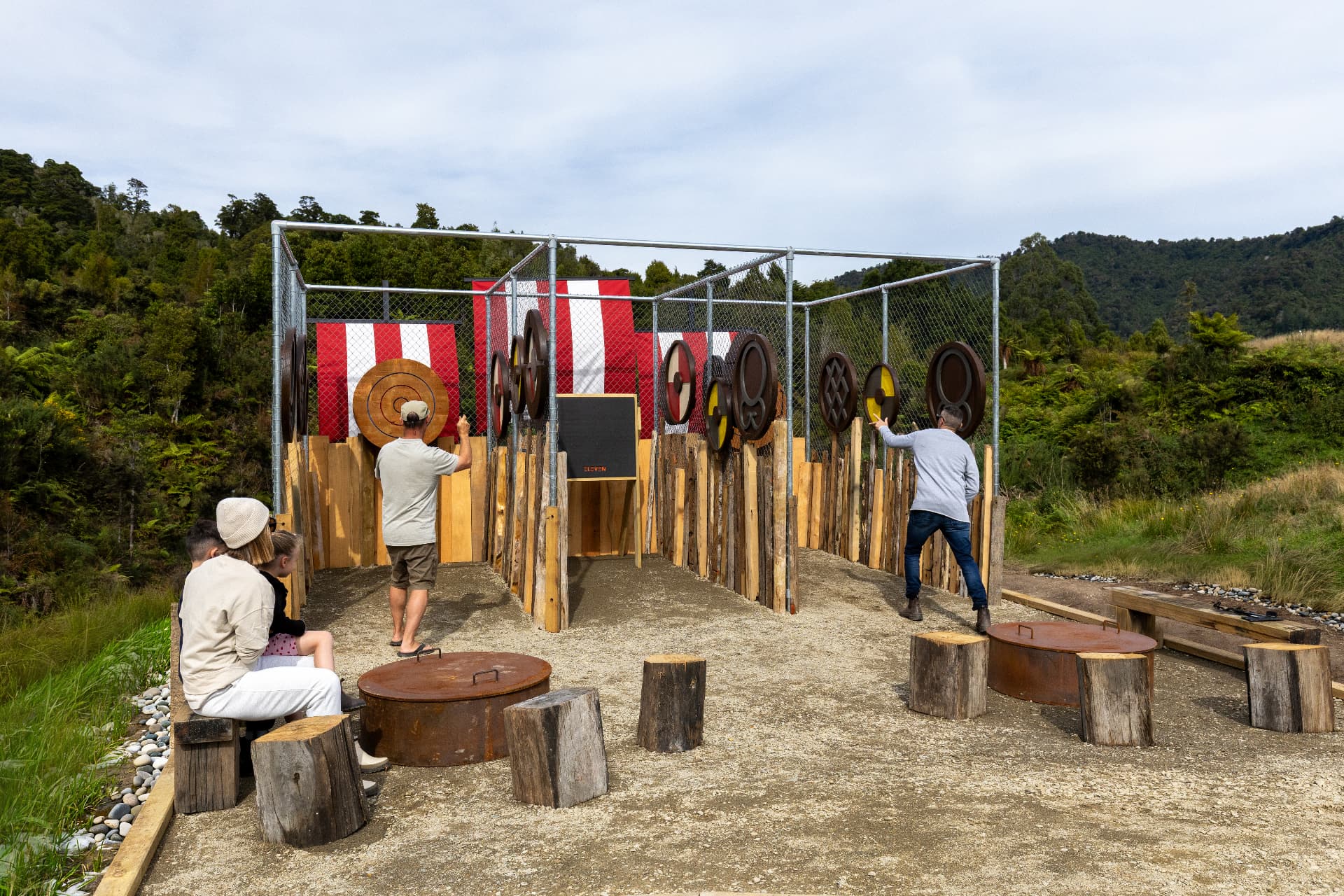 Guests throwing axes at shield targets inside the caged range